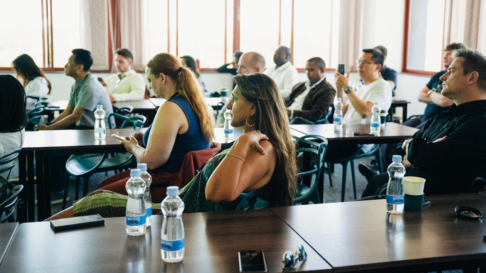 Des participants assis à des tables dans une salle de séminaire lumineuse