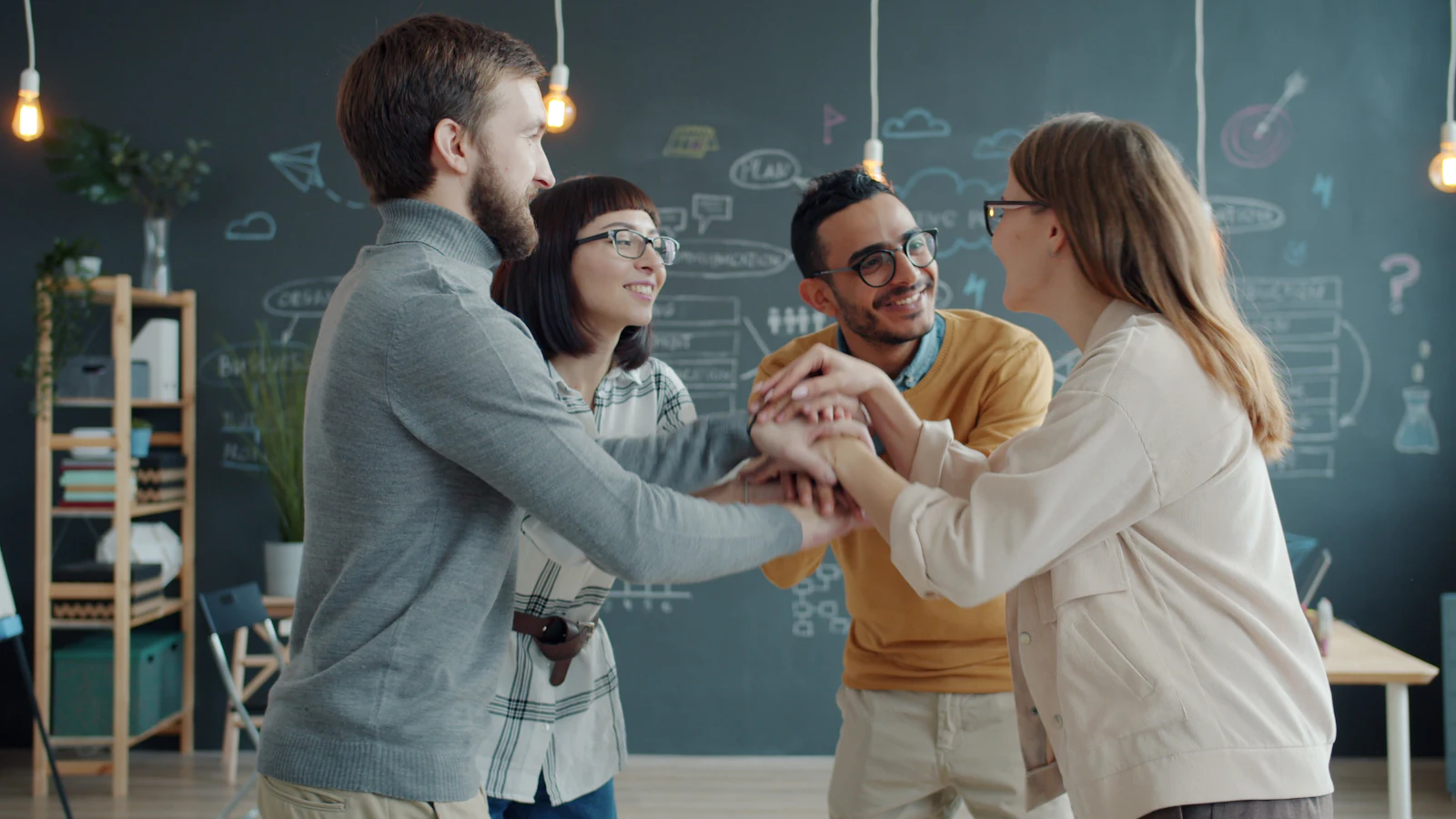Quatre collègues réunissent leurs mains en souriant