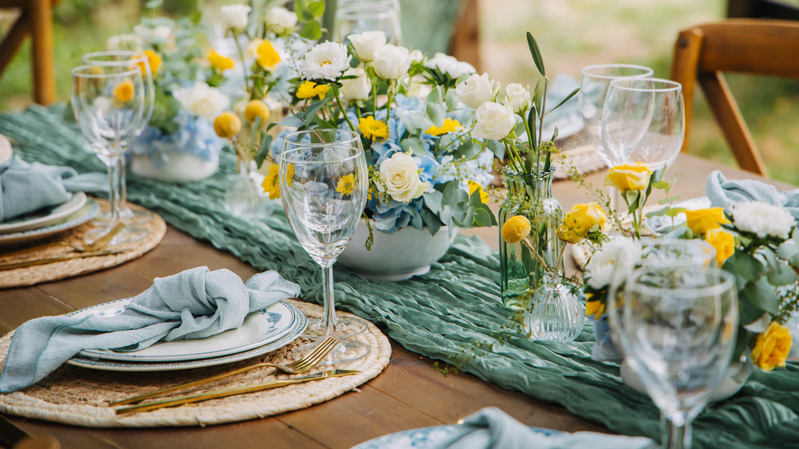 Une table dressée avec des fleurs blanches et jaunes, des verres et des assiettes