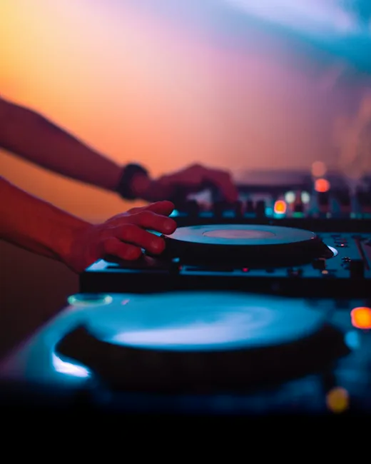 Mains d'un DJ sur les platines à la tombée du jour