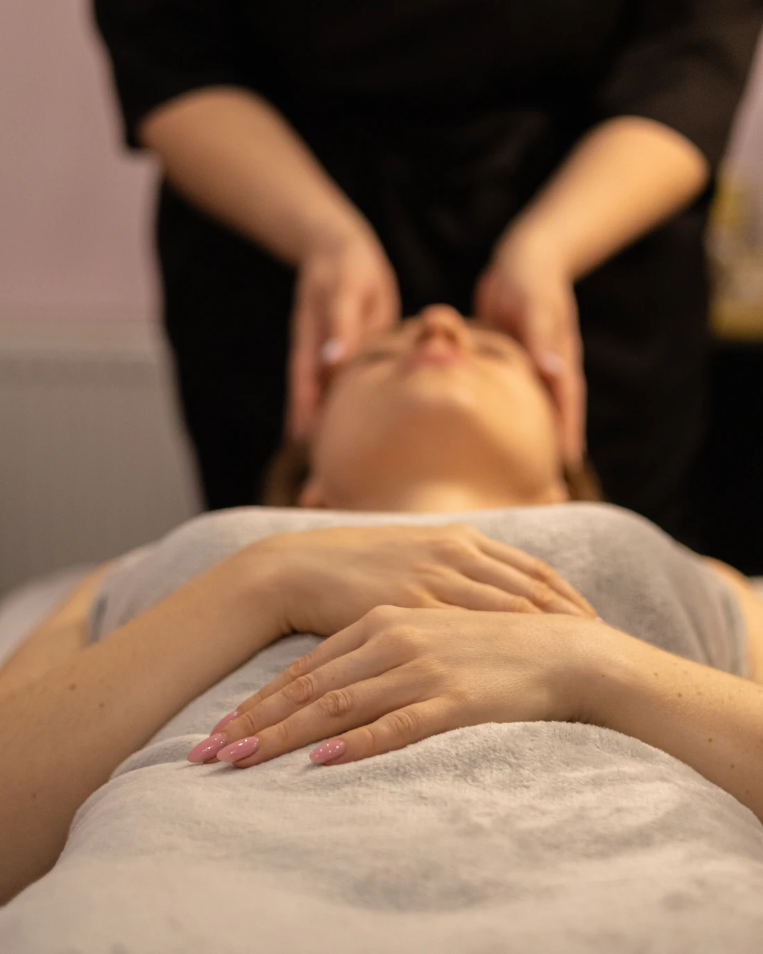 Modelage du visage, la cliente allongée sous une serviette, ongles roses