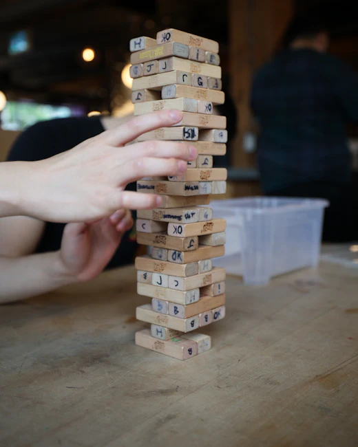 Main retirant une pièce d'une tour de jeu en bois