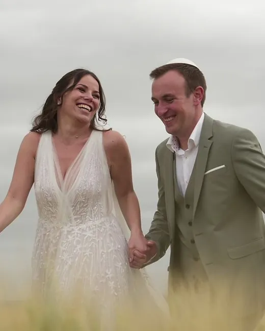 Un couple de mariés main dans la main dans un champ