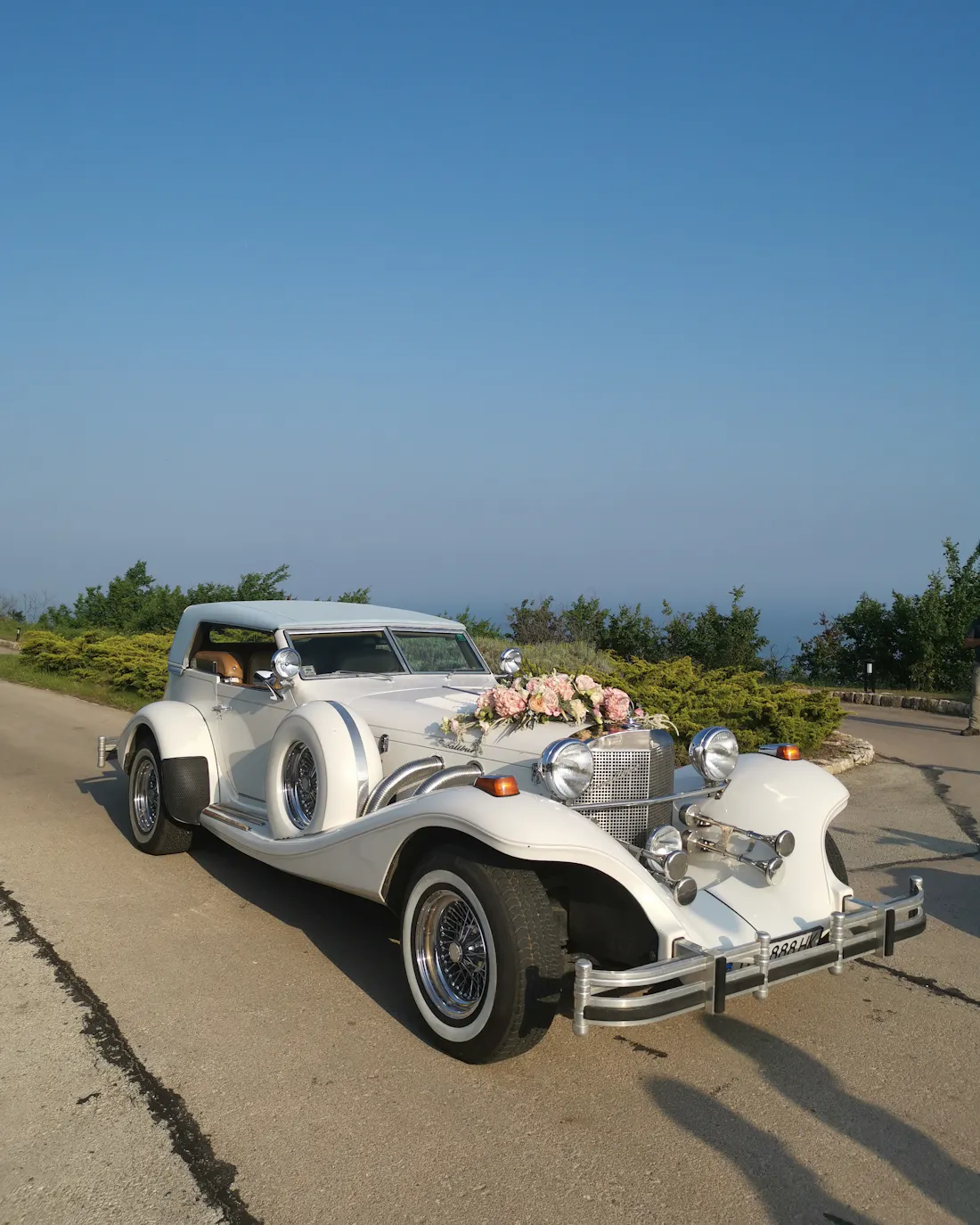 Voiture ancienne blanche décorée de fleurs au bord d'une route